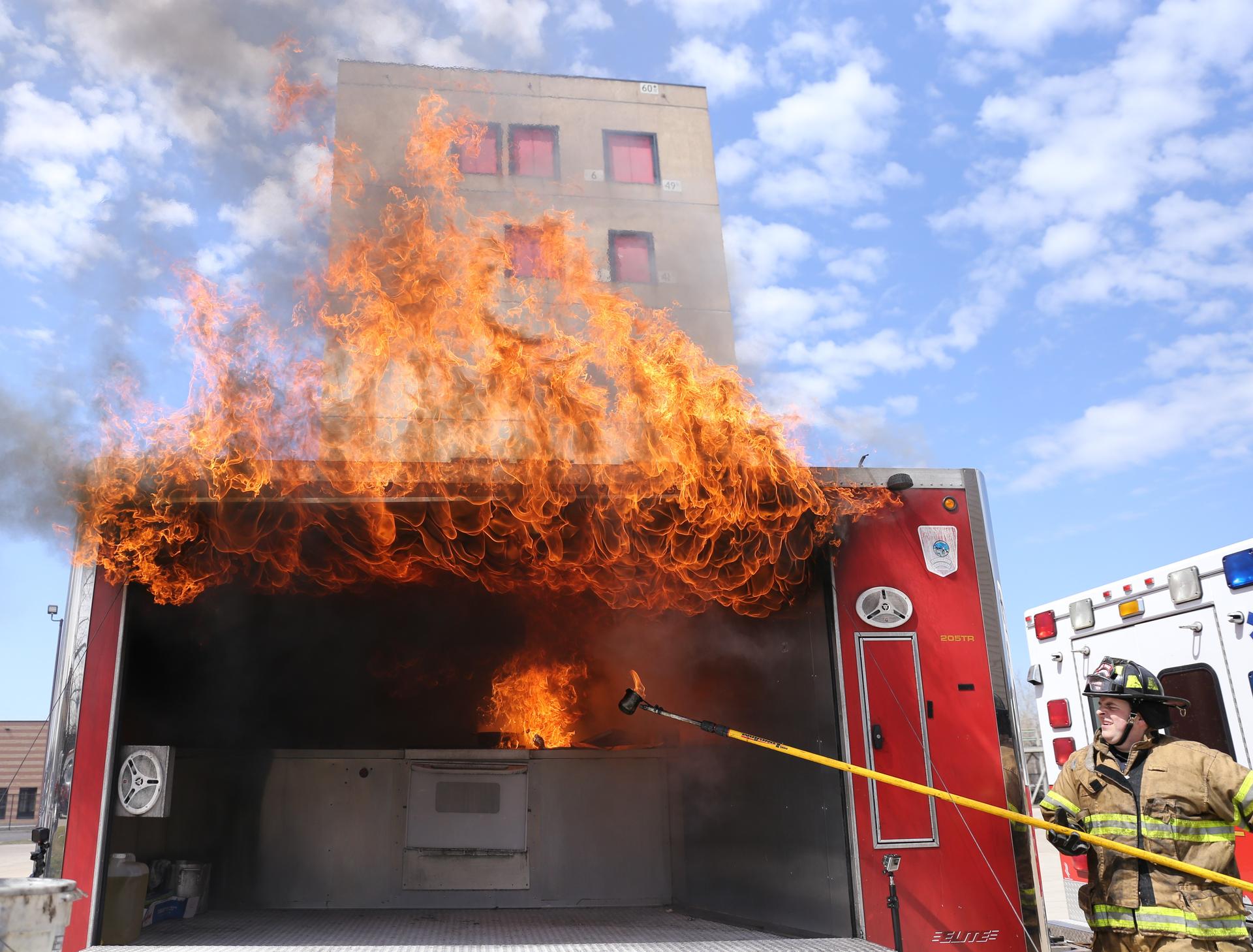 A firefighter pours water on a grease fire as a demonstration.