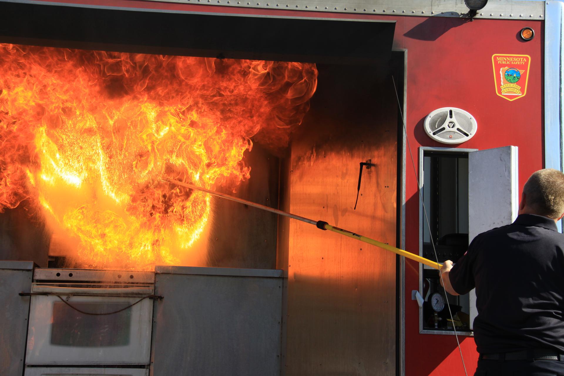 A firefighter pours water on a grease fire as a demonstration.