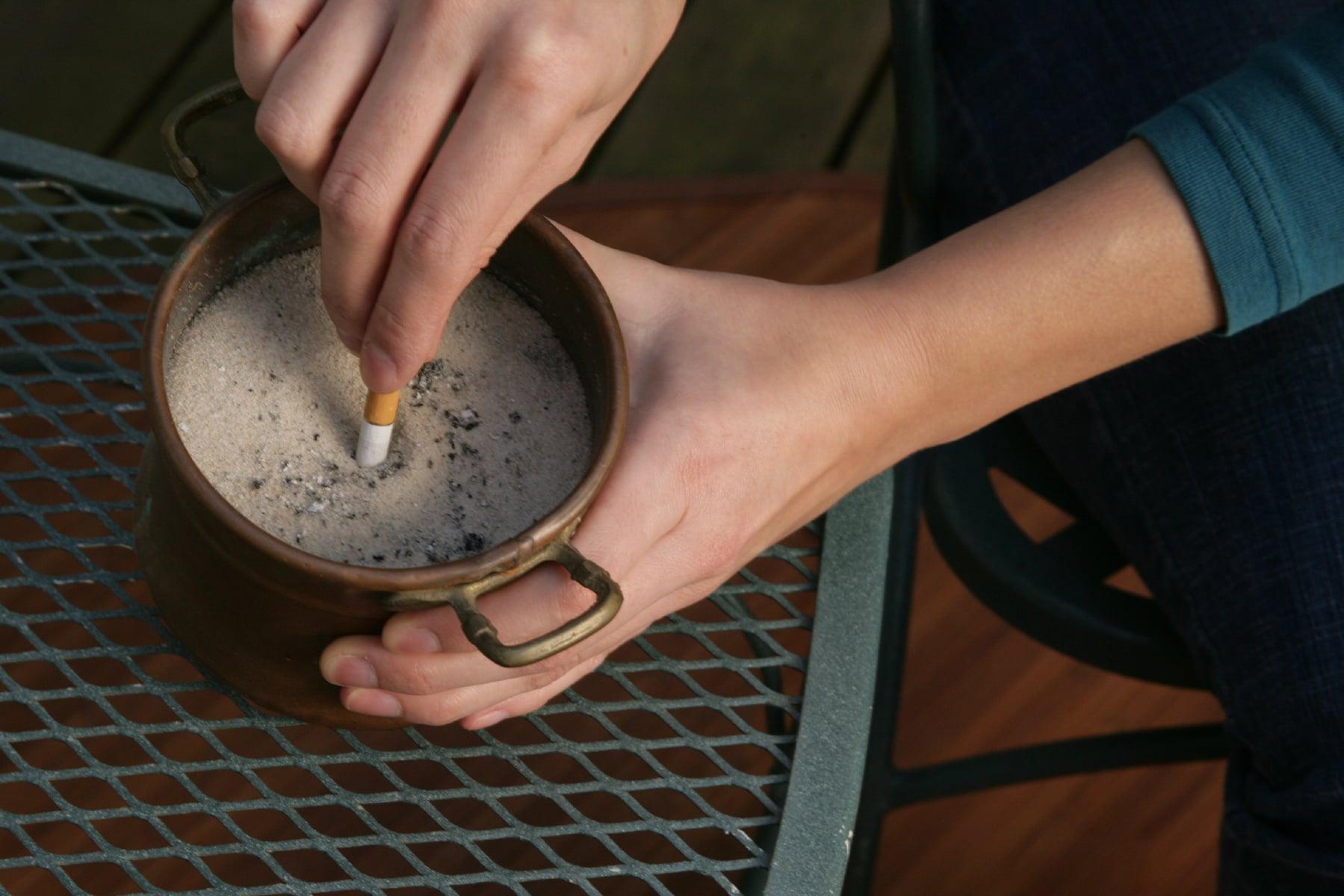 A woman puts out a cigarette in an ashtray.