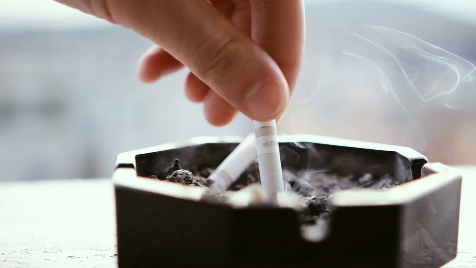 A woman puts out a cigarette in an ashtray.